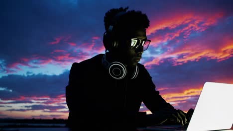 young person working on a laptop at sunset