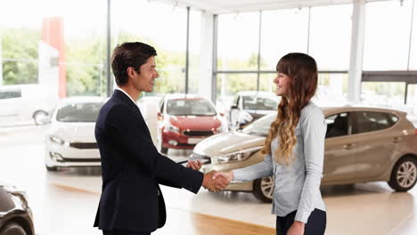 hombre y mujer caucásicos estrechando la mano en un distribuidor de automóviles