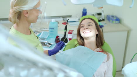 mujer en un chequeo dental regular en el consultorio del dentista. niña feliz en la silla dental