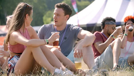 couple sitting on grass talking at music festival