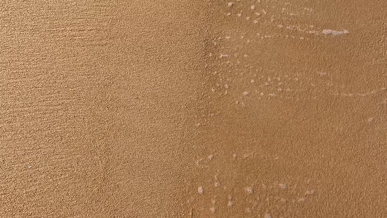 Waves gently wash over sandy beach in Phuket, Thailand, creating a serene and calming atmosphere