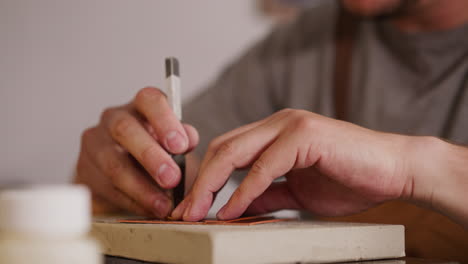 Leathersmith-makes-holes-in-workpiece-with-fork-at-table