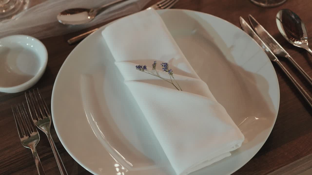Piatto bianco con tovagliolo piegato e posate disposte su tavolo di legno