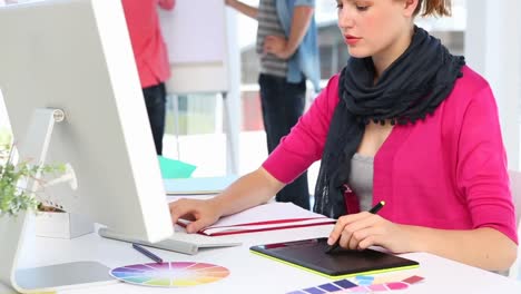 Pretty-designer-working-with-graphics-tablet-at-her-desk