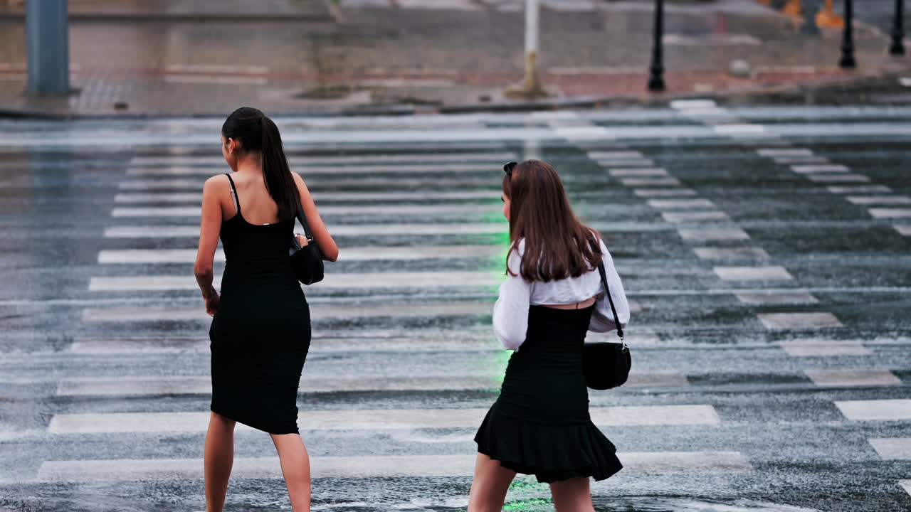 Two girls crossing the street at a green light on a rainy day in Chisinau, Moldova