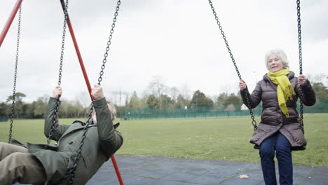 Pareja-Mayor-Divirtiéndose-Jugando-En-Columpios-En-El-Parque-Infantil