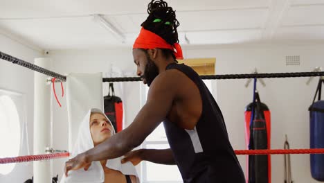 Trainer-giving-massage-to-female-boxer-in-boxing-ring-4k