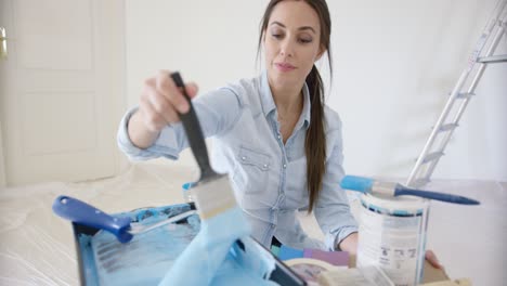 una joven sonriente chequeando una pintura azul