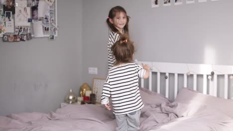 dos hermanas pequeñas están saltando en una cama y cayendo en ella. caras sonrientes. cámara lenta