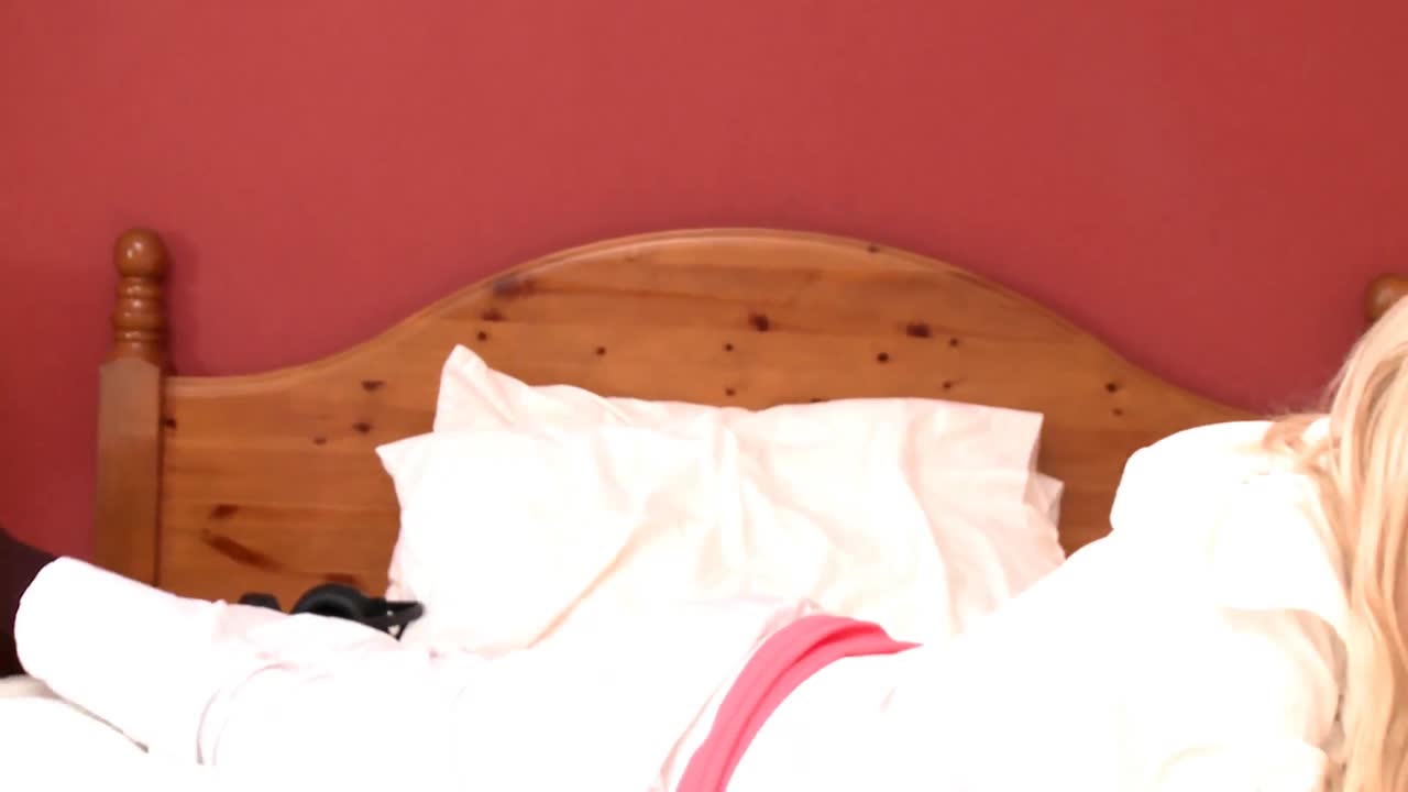 예쁜 여자가 전화로 침대에 앉아 있습니다.