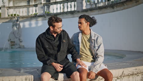 two men talking in a park near a fountain