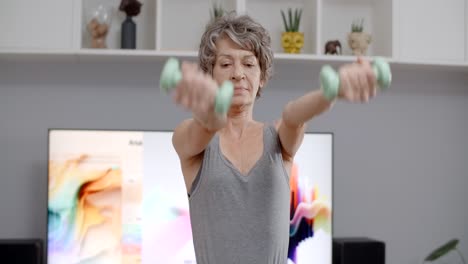 senior woman exercising at home with dumbbells