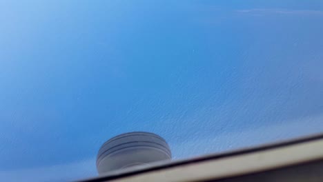 Looking-out-window-of-small-aeroplane-at-view-of-the-landing-gear-wheel-and-stunning-turquoise-blue-green-ocean-water-in-the-Coral-Triangle-of-Timor-Leste,-Southeast-Asia