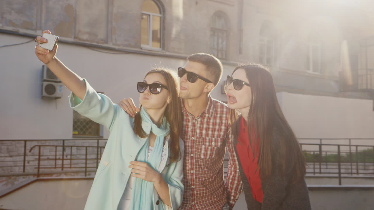 un grupo de amigos hace selfie hacen una cara graciosa los rayos rojos del sol sobre un fondo de un