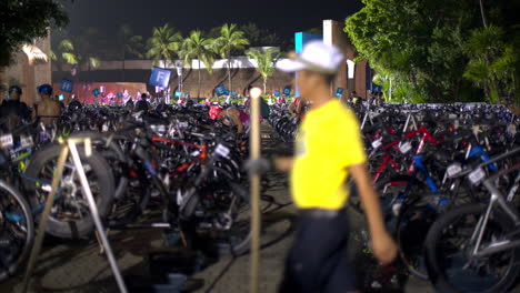 athletes gathering for a triathlon inspecting their bikes early in the morning at nighttime wearing swimsuits and helmets