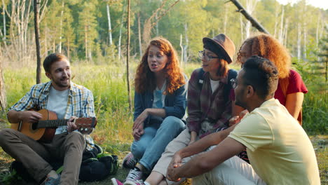 friends singing and playing guitar in a forest