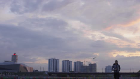 donna sportiva in felpa con cappuccio che corre in città mentre si allena all'aperto al mattino presto