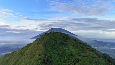 Drone fly rising up show the scenery the peak of Telomoyo Mountain with Merbabu Mountain background, Indonesia rural landscape.