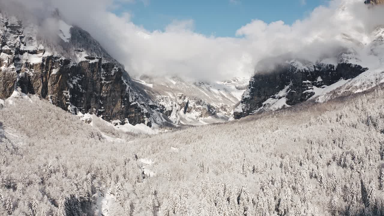 An Aerial View of Cirque du Fer à Cheval while covered in snow during a cold winter, pointing down valley at the bout du monde with a sun covered frosted forest bed