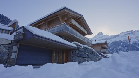 Low-angle-dolly-of-a-beautiful-wooden-chalet-covered-in-snow-on-a-early-winter-day