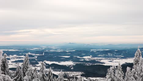 Scenic-far-view-from-hill-over-rugged-countryside-terrain,-snowy-treetop