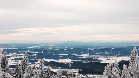 scenic far view from hill over rugged countryside terrain, snowy treetop