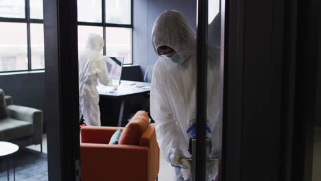 cleaners wearing protective clothes sanitizing modern office space