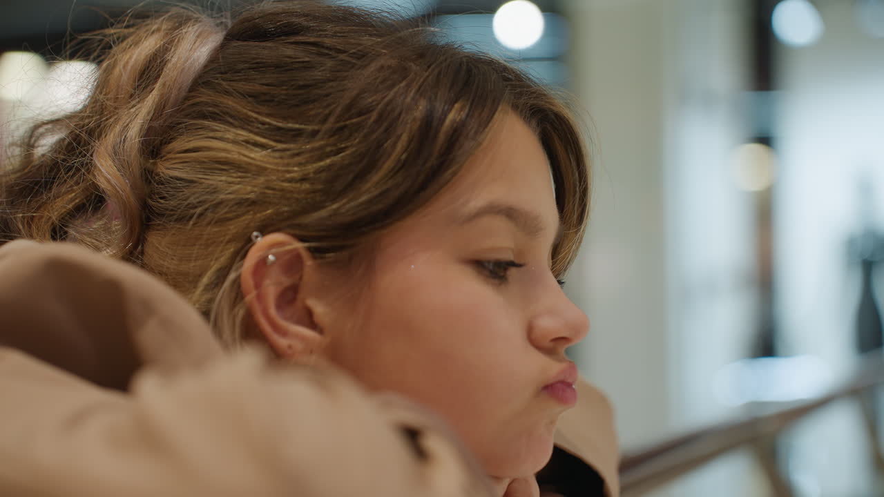 teenager observing calmly in store, pensive adolescent in shopping mall with gentle lighting scene, teen girl with light braid appears reflective amidst quiet retail environment scene