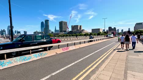 cyclists and pedestrians share a sunny london bridge