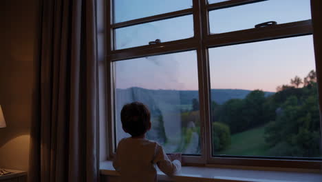 child looking out the window at sunset