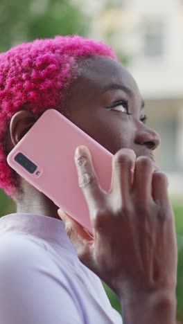 person with pink hair talking on a pink smartphone