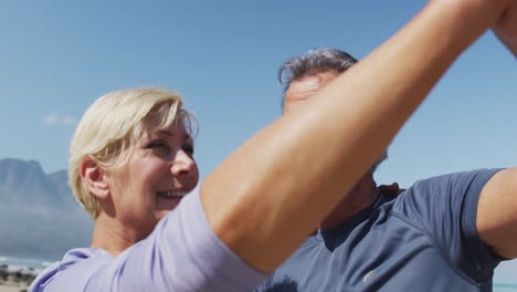 senior hiker couple dancing on the beach while hiking.