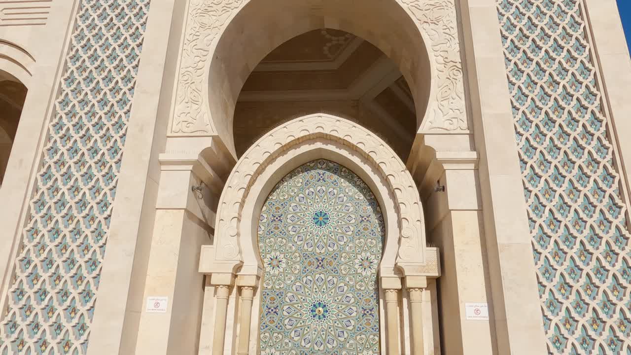 Looking down majestic Hassan ii mosque marble tower to decorative Arabic patterned mosaic fountain