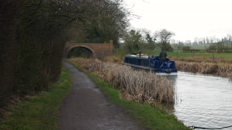 Ein-Schmales-Hausboot,-Das-Im-Regen-Entlang-Eines-Kanalflusses-In-England-Fährt