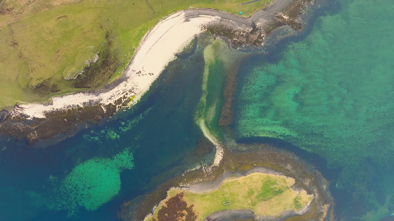 Aerial drone shot of Coral Beach on the Isle of Skye, Scotland, with turquoise waters, white sand, and surrounding green hills creating a stunning coastal landscape