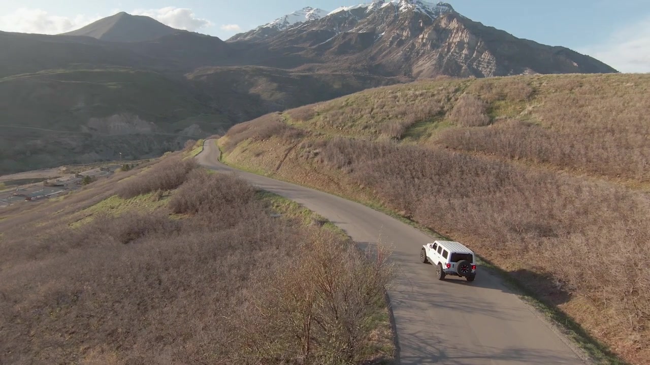 Raggi di sole al tramonto che si irradiano sulla cresta delle montagne Wasatch dello Utah - Vista aerea. Seguendo il SUV bianco