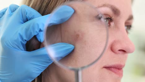dermatologist examining a patient's skin with a magnifying glass