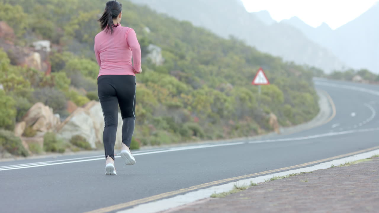 Jogging on mountain road, woman in athletic wear enjoying outdoor exercise, copy space