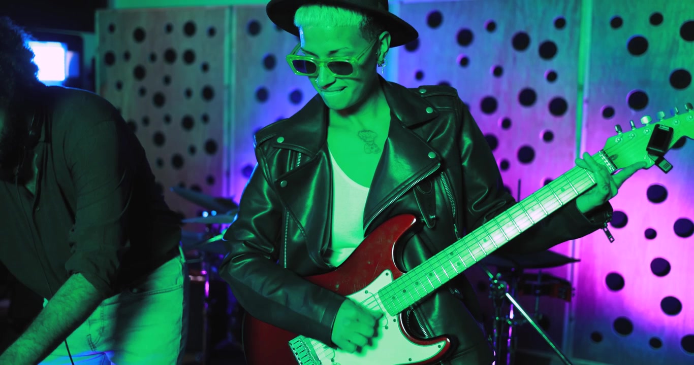 Coole Musiker spielen E-Gitarre und legen in einem Neon-Studio auf