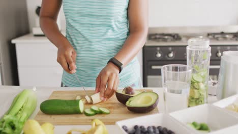 midsection of african american woman cutting vegetables in kitchen