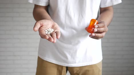 person holding pills and pill bottle