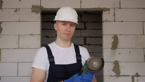 portrait of a smiling construction worker in a white helmet with a circular saw.