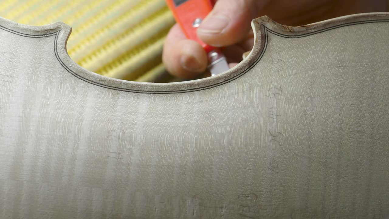 macro close up of artisan luthier maker work on new classic handmade raw violin smooth edge in waist and purfling rasp in workbench of workshop in Cremona Italy 4k video