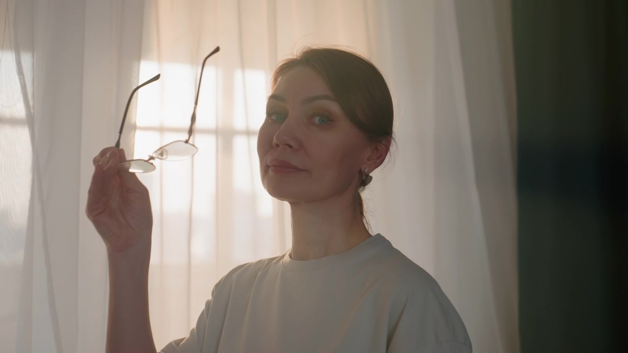 Caucasian woman livingroom reading book, seasoned grammar coach adjusting glasses with confident gaze in warm window light, poised presentation with subtle smile, curtain backdrop and soft golden