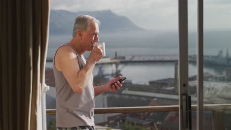 Senior-man-using-his-mobile-phone-and-drinking-coffee