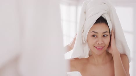 화장실 에서 거울 을 바라보는 머리카락 에 수건 을 쓴 미소 짓는 두 인종 의 여성 의 초상화 의 비디오