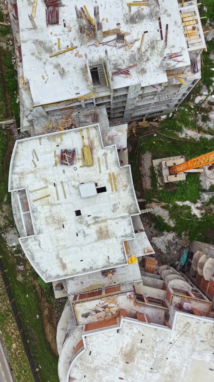 Construcción de edificio de varias plantas en un sitio urbano con áreas abiertas y trabajo en curso en el nivel superior.