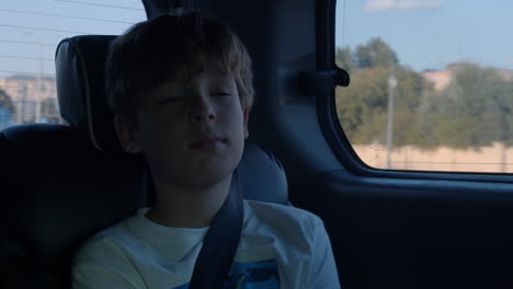 boy with fastened seat belt traveling by car