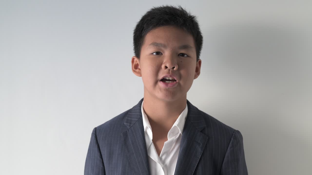 Portrait of Asian teenage boy talking and looking at camera against white background