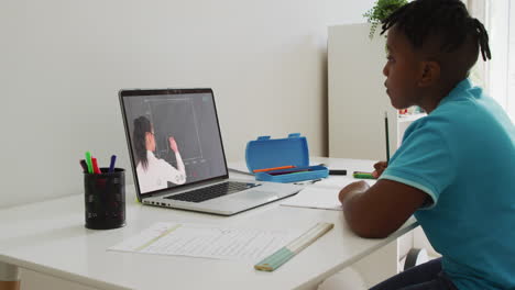 african american boy sitting at desk using laptop having online school lesson